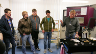 Lutz Müller (r.), Mitarbeiter im Optiklabor, erklärt einer Gruppe Schülern, wie Linse